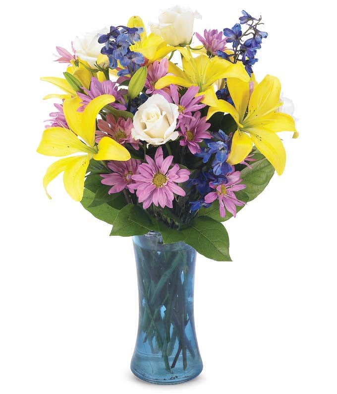Yellow lilies and purple daisies in a colorful vase