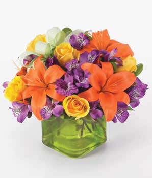 Orange lilies, yellow roses and purple alstroemeria in a square glass vase