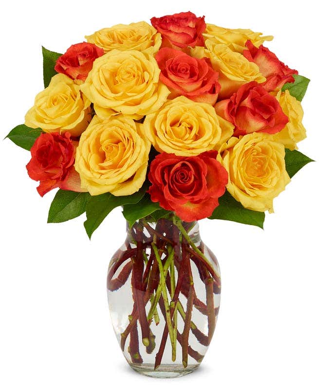 Yellow rose and orange roses in a glass vase
