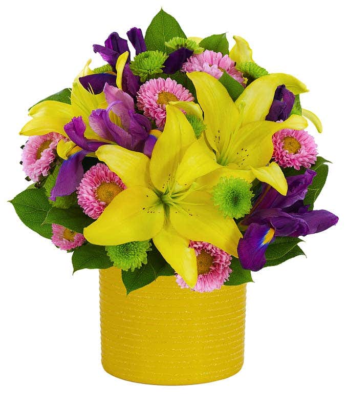 Yellow lilies, pink asters and irises in a yellow pot for delivery