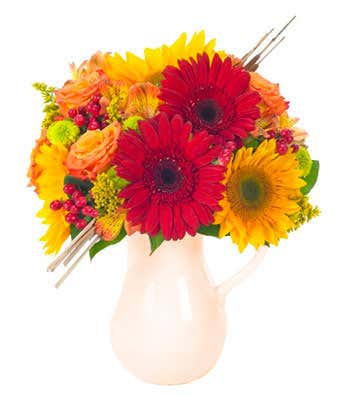 Orange roses, red gerbera daises and hypericum in pitcher for Fall