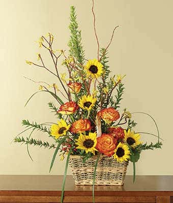 Orange roses and sunflowers in woven basket