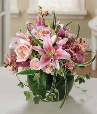 Pink roses, pink orchids and white lilies in a circular arrangement 