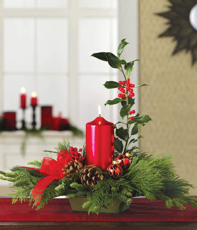 Large red candle in the center of a white pine centerpiece