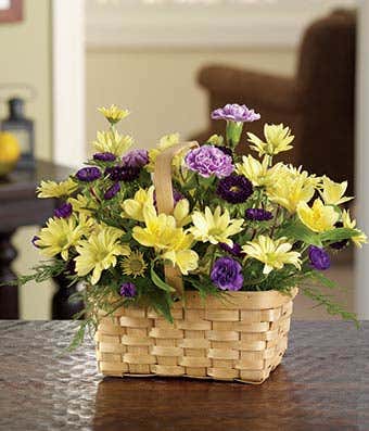 Purple asters, yellow alstroemeria and daisies in a woven basket