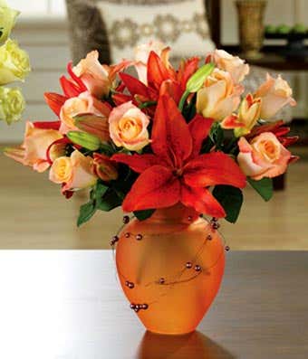 Orange lilies and orange roses in tangerine vase