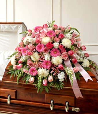 Pink roes, pink gerbera daisies and white flowers in a casket cover
