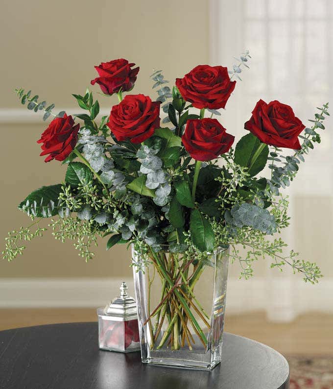 Red roses and eucalyptus in a modern glass vase