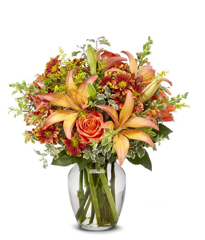 Bo-colored lilies, orange roses and Fall daisies in an orange vase for Fall