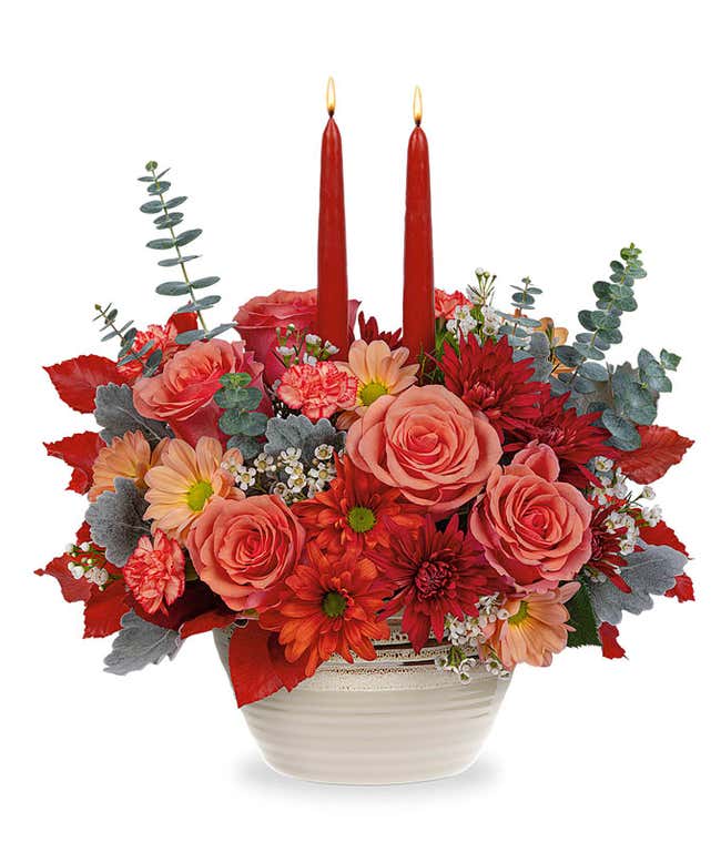 Orange Roses &amp; Carnations, Beige, bronze, and dark bronze chrysanthemums, spiral eucalyptus, red copper beech, and dusty miller in a beige rustic bowl with two burgundy taper candles